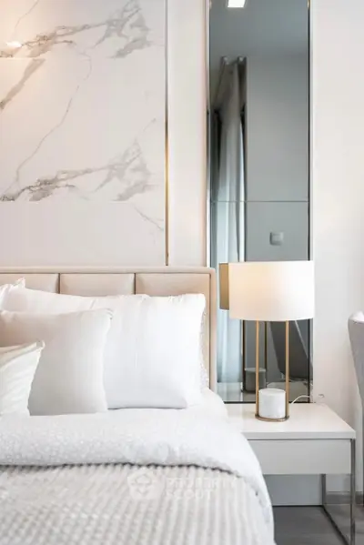 Luxurious bedroom with elegant marble accent wall and modern bedside lamp.