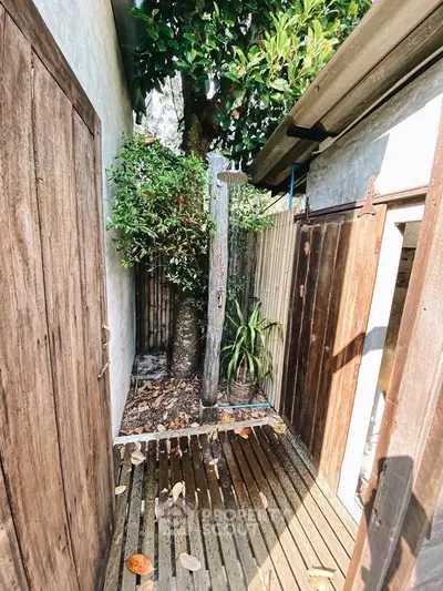 Charming rustic outdoor shower area with wooden accents and lush greenery, perfect for nature lovers.