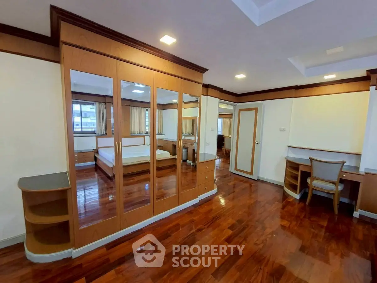 Spacious bedroom with elegant wooden flooring and mirrored wardrobe