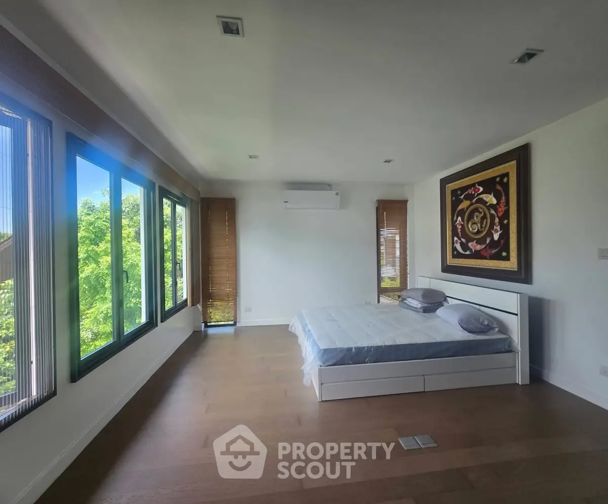 Spacious bedroom with large windows and modern decor, offering serene views and abundant natural light.