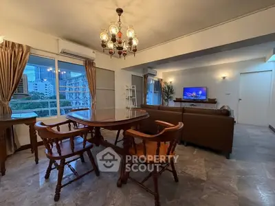 Spacious living room with elegant chandelier and city view, featuring classic wooden dining set and cozy seating area.