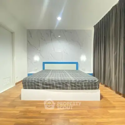 Modern bedroom with stylish marble accent wall and wooden flooring