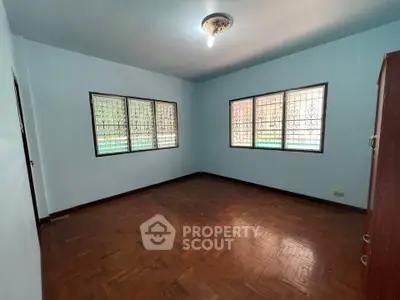 Spacious empty room with wooden flooring and large windows, ideal for customization.