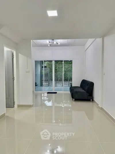 Spacious living room with sleek tile flooring and modern sofa, featuring large sliding glass doors to balcony.