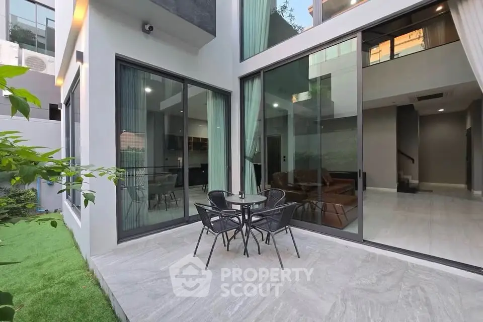 Modern home exterior with large glass doors and cozy patio area