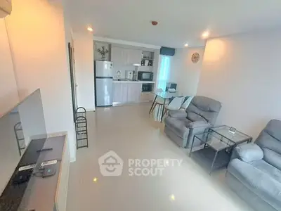 Modern open-layout living room with kitchen, featuring cozy seating and sleek appliances.