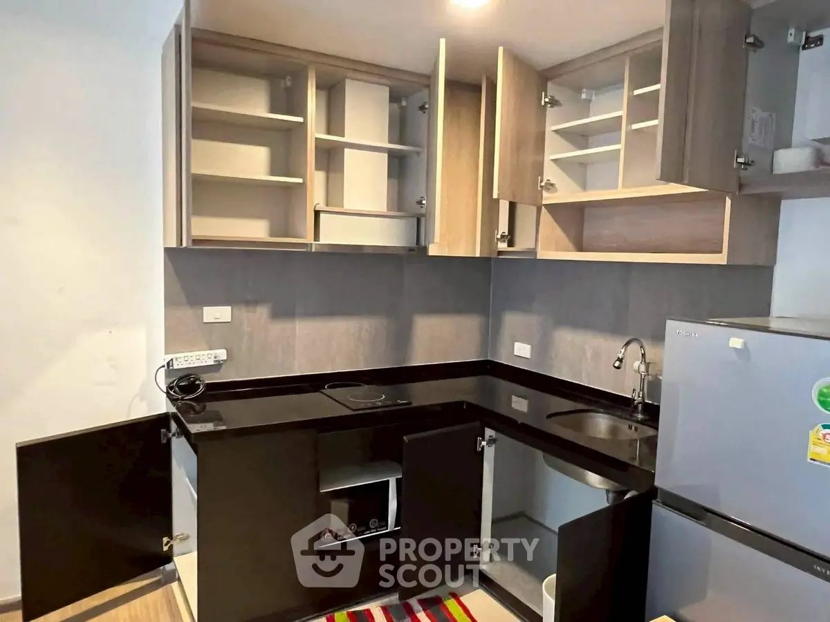Modern kitchen with sleek black countertops and ample cabinet space in a contemporary apartment.