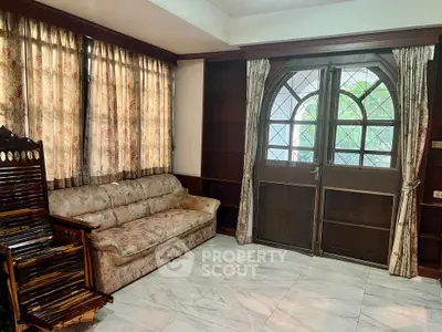 Charming living room with vintage furniture and large windows, perfect for cozy gatherings.