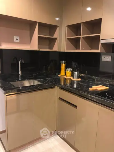 Modern kitchen with sleek cabinetry and black marble countertops in a stylish apartment.