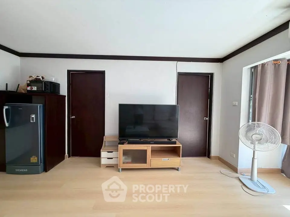 Modern living room with TV, fan, and sleek wooden flooring