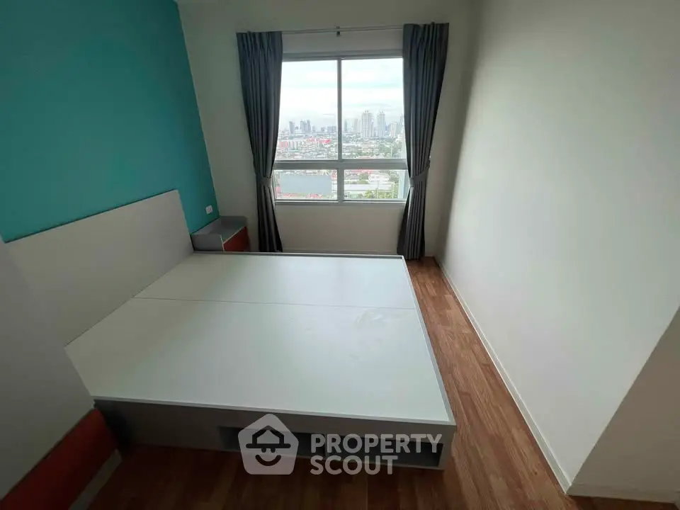 Modern bedroom with city view, featuring a sleek bed and large window for natural light.