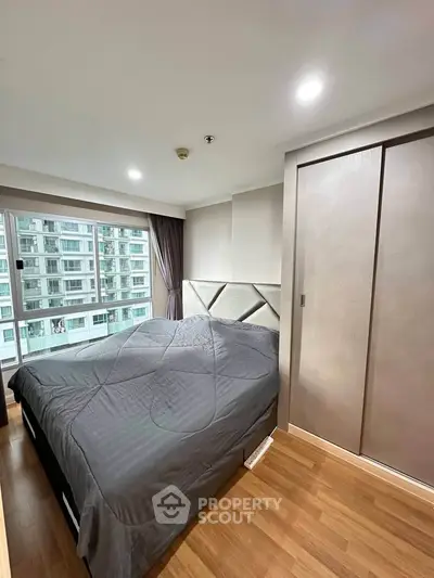 Modern bedroom with large window and built-in wardrobe in urban apartment