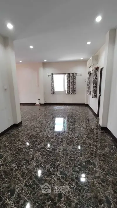 Spacious living room with marble flooring and natural light