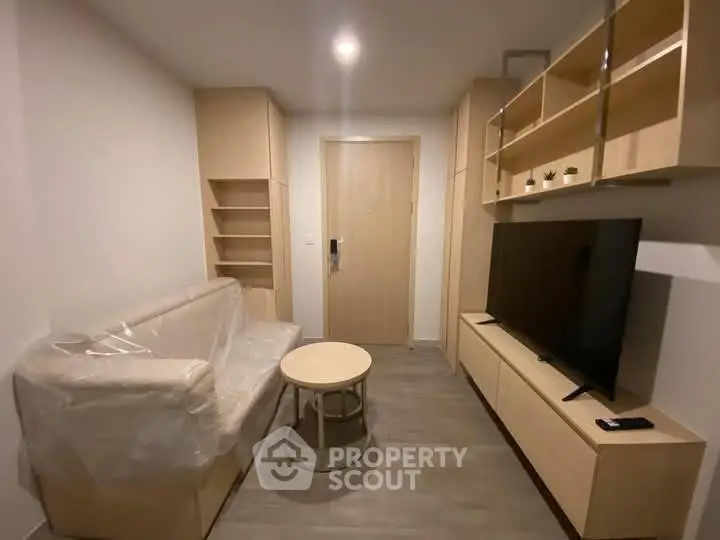 Modern living room with sleek furniture and large TV in a cozy apartment setting.