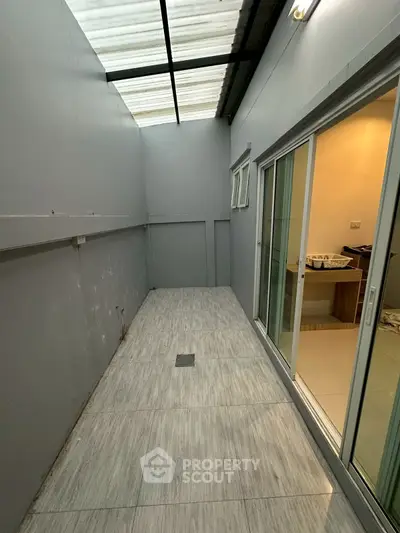 Spacious covered outdoor area with sliding glass doors and tiled flooring