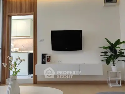 Modern living room with wall-mounted TV and view into sleek kitchen