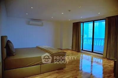 Spacious bedroom with polished wooden floors and city view balcony.