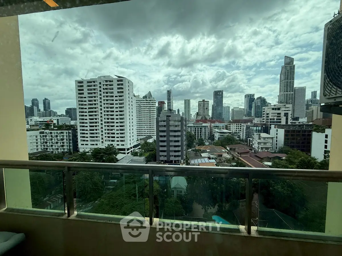 Stunning cityscape view from a high-rise balcony, showcasing urban skyline and lush greenery.