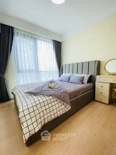 Modern bedroom with stylish decor and large window offering natural light