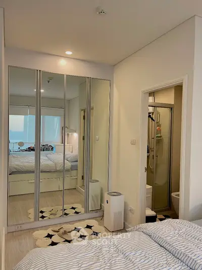 Modern bedroom with mirrored wardrobe and ensuite bathroom in stylish apartment