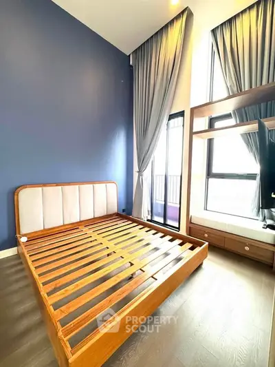 Spacious bedroom with high ceilings and large windows, featuring a modern wooden bed frame and elegant curtains.