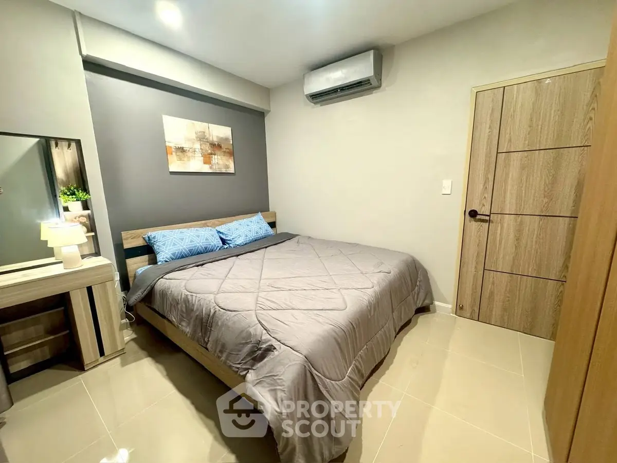 Cozy bedroom with modern decor and air conditioning, featuring a comfortable bed and stylish wooden furniture.