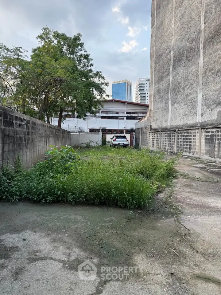 Vacant urban lot with potential for development, featuring city skyline views and lush greenery.