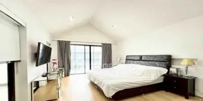 Spacious bedroom with modern decor and large windows for natural light.