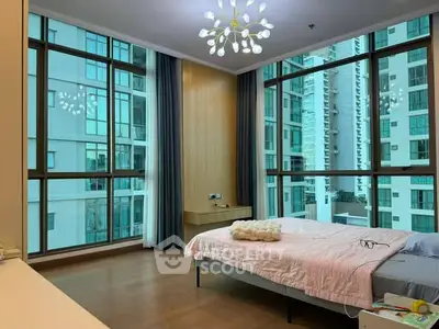 Spacious bedroom with large windows and modern lighting in a high-rise building.