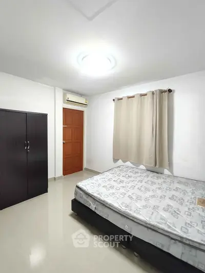 Spacious bedroom with minimalist decor and ample natural light.