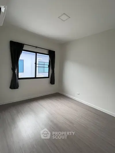 Spacious empty room with large window and elegant curtains, perfect for customization.