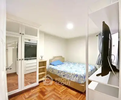 Cozy bedroom with mirrored wardrobe and wooden flooring in modern apartment.