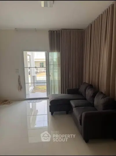 Spacious living room with elegant curtains and modern sofa, featuring a bright and airy ambiance.
