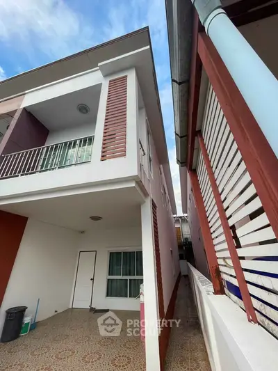 Modern two-story house with balcony and tiled exterior in a suburban neighborhood.