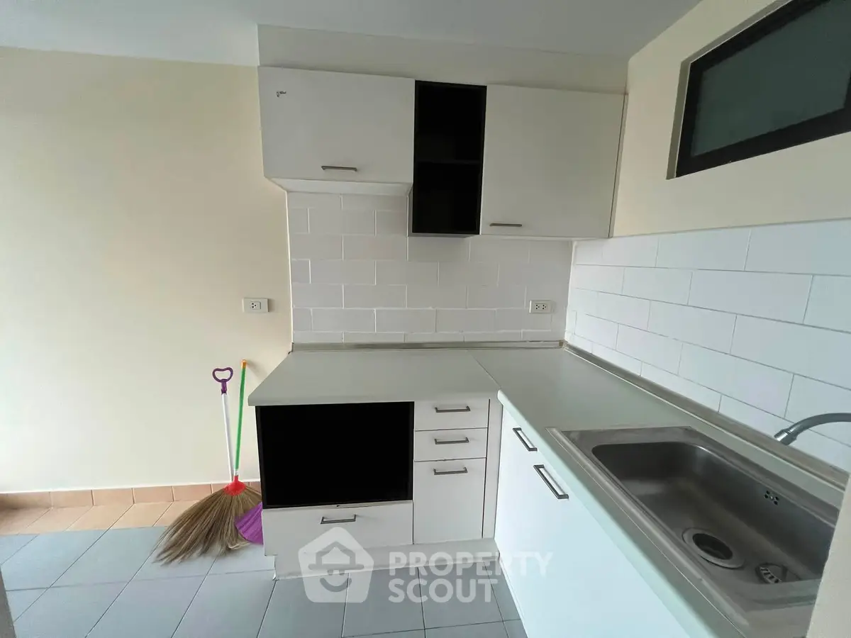 Modern kitchen with sleek white cabinets and stainless steel sink in a compact layout.