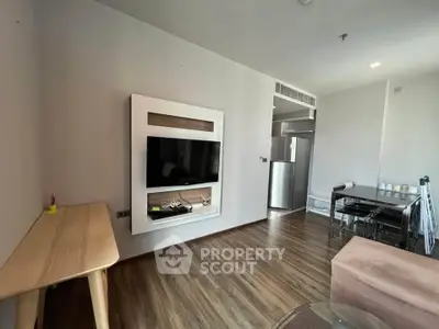 Modern living room with sleek TV setup and dining area, featuring wooden flooring and contemporary furniture.