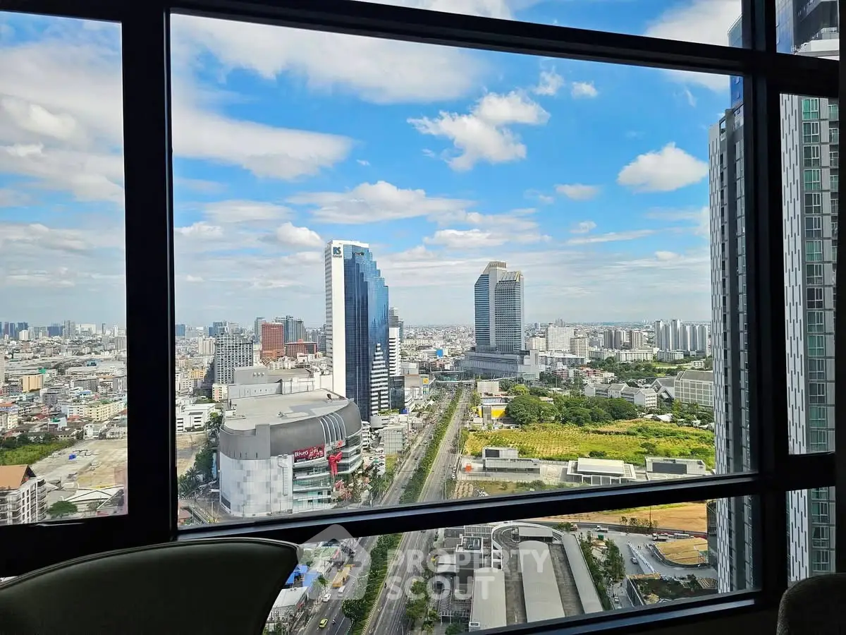 Stunning cityscape view from high-rise building window showcasing urban skyline and blue sky.