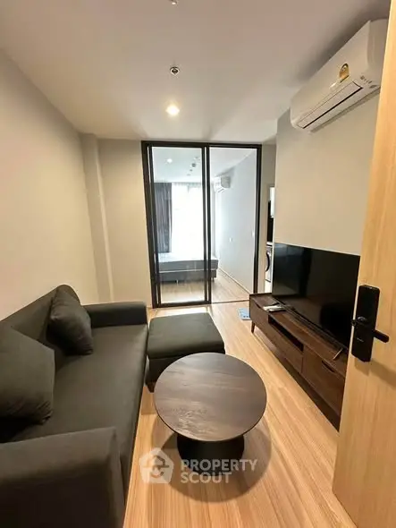 Modern living room with sleek furniture and glass partition in stylish apartment.
