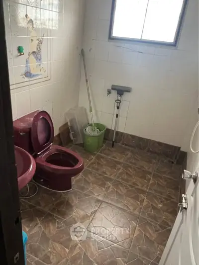Unique bathroom with maroon fixtures and tiled flooring, featuring a window for natural light.