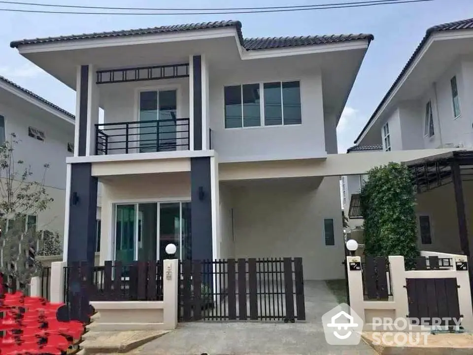 Modern two-story house with sleek design and gated driveway in suburban neighborhood.