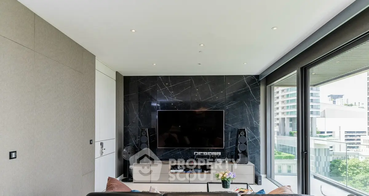 Modern living room with sleek TV setup and large windows offering city views.