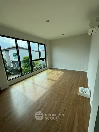 Spacious empty room with large windows and wooden flooring, perfect for customization.