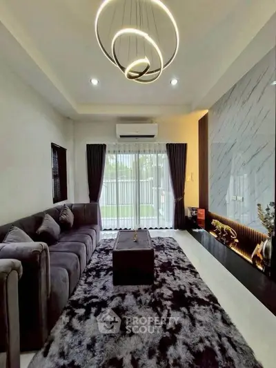 Luxurious living room with modern chandelier and plush sofa, featuring elegant decor and natural light.