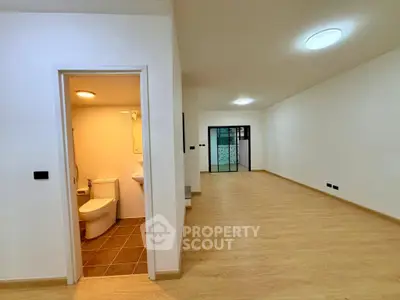 Spacious open-plan living area with modern bathroom and sleek wooden flooring.