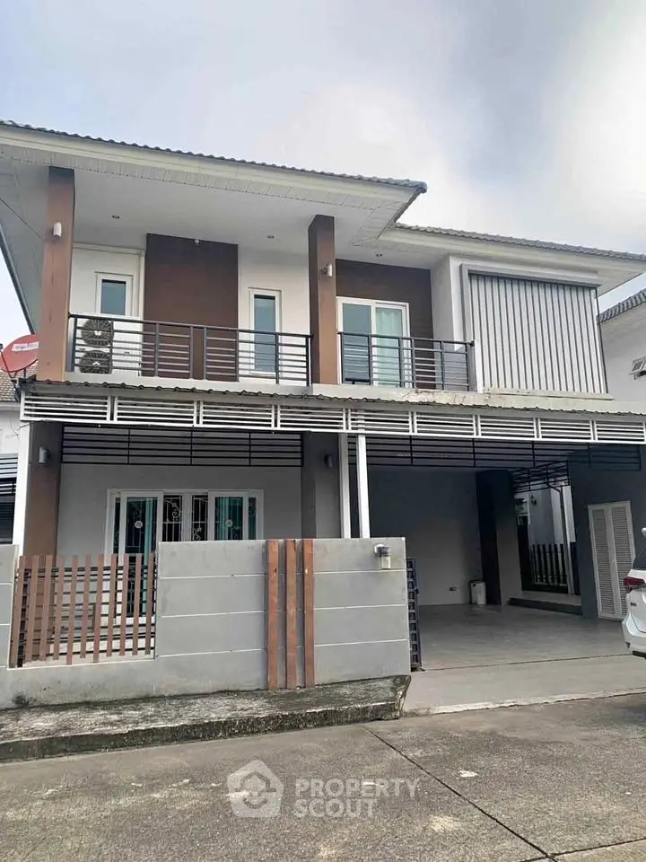 Modern two-story house with balcony and spacious driveway in suburban neighborhood.