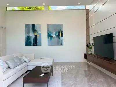 Modern living room with stylish decor and large TV, featuring elegant artwork and sleek furniture.
