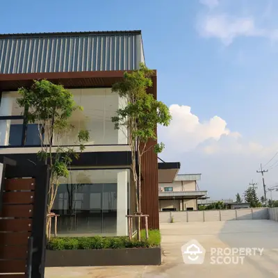 Modern commercial building with sleek design and spacious parking area under clear blue sky.