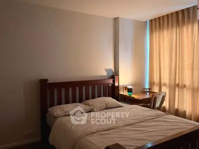 Cozy bedroom with wooden bed frame and natural light through curtains