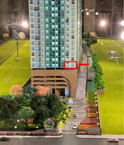 Scale model of modern high-rise building with landscaped surroundings and driveway.