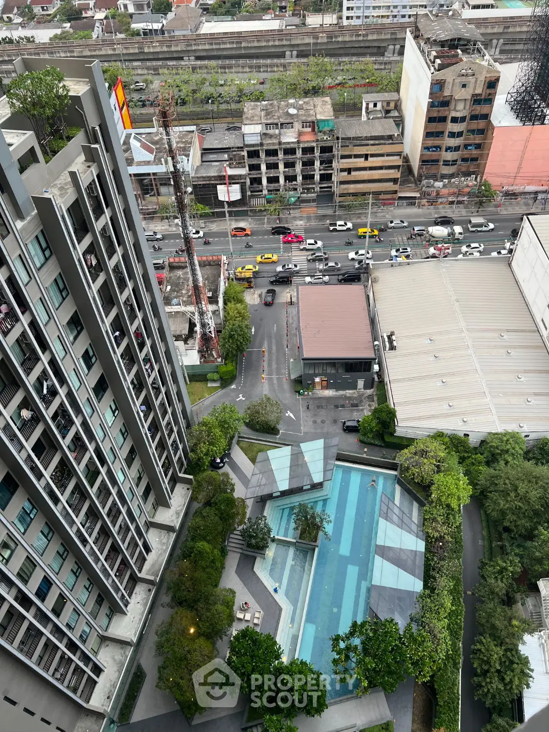 Stunning aerial view of modern high-rise building with pool and cityscape backdrop.